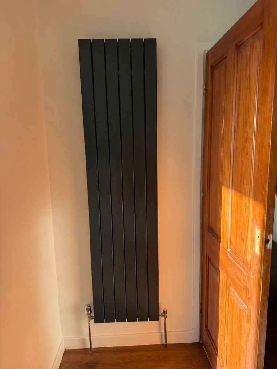 Black vertical designer radiator with chrome valves fitted by LR Heating, Leeds