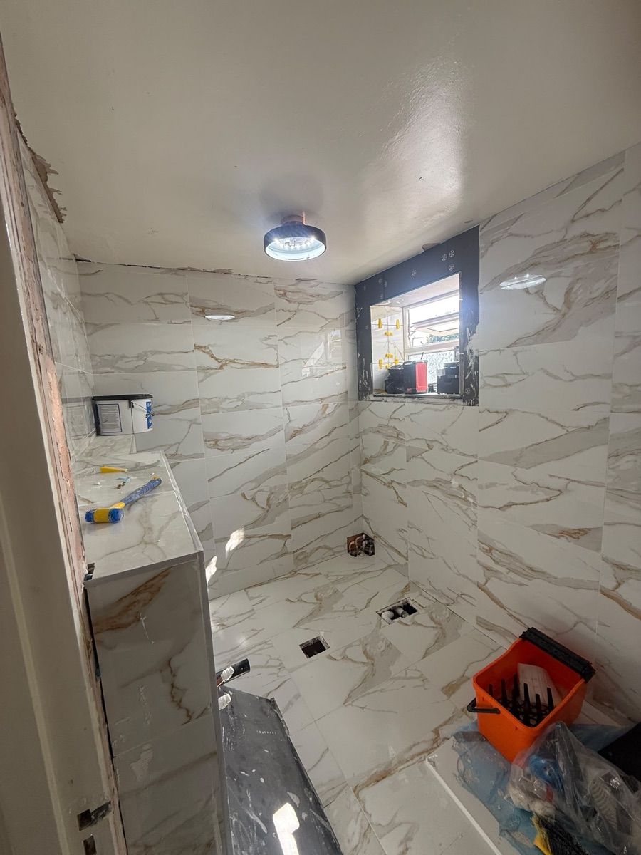 Marble-effect wall tiling in progress around a new walk-in shower by LR Heating